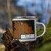 Right View Custom Bay City Michigan Map Enamel Mug in Ember on Grass With Trees in Background