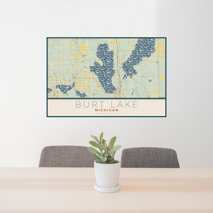 24x36 Burt Lake Michigan Map Print Landscape Orientation in Woodblock Style Behind 2 Chairs Table and Potted Plant