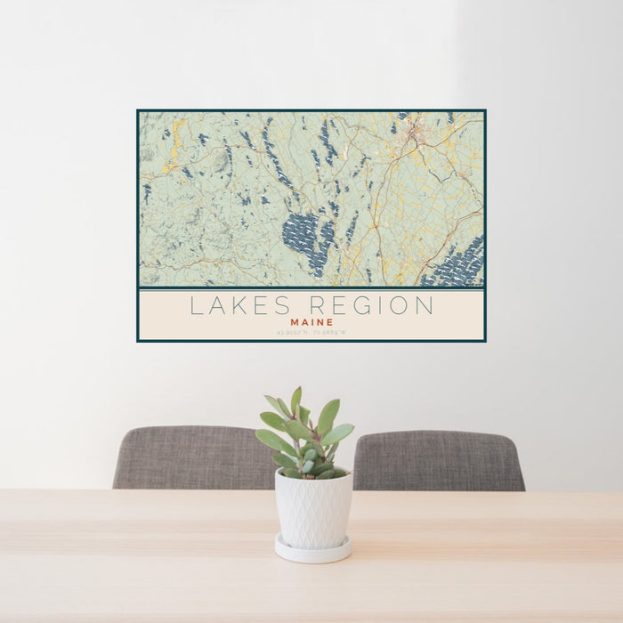 24x36 Lakes Region Maine Map Print Lanscape Orientation in Woodblock Style Behind 2 Chairs Table and Potted Plant