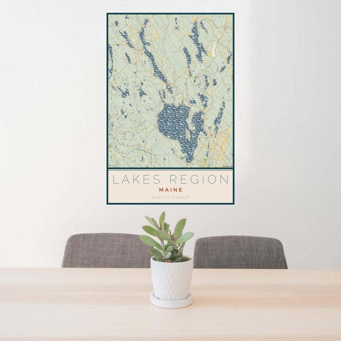 24x36 Lakes Region Maine Map Print Portrait Orientation in Woodblock Style Behind 2 Chairs Table and Potted Plant