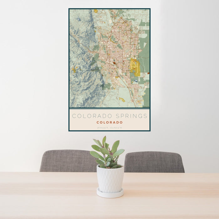 24x36 Colorado Springs Colorado Map Print Portrait Orientation in Woodblock Style Behind 2 Chairs Table and Potted Plant