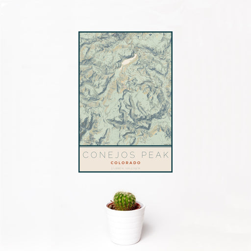 12x18 Conejos Peak Colorado Map Print Portrait Orientation in Woodblock Style With Small Cactus Plant in White Planter