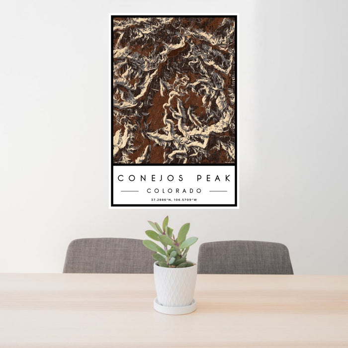 24x36 Conejos Peak Colorado Map Print Portrait Orientation in Ember Style Behind 2 Chairs Table and Potted Plant