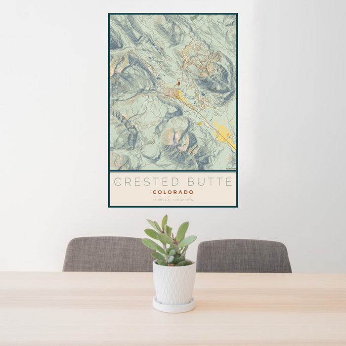 24x36 Crested Butte Colorado Map Print Portrait Orientation in Woodblock Style Behind 2 Chairs Table and Potted Plant