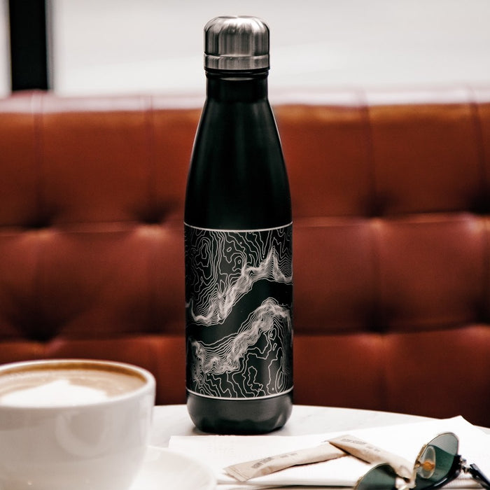 17oz Stainless Steel Insulated Cola Bottle in Black with Custom Engraved Map on Table in Front of Red Bench