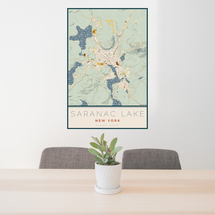 24x36 Saranac Lake New York Map Print Portrait Orientation in Woodblock Style Behind 2 Chairs Table and Potted Plant