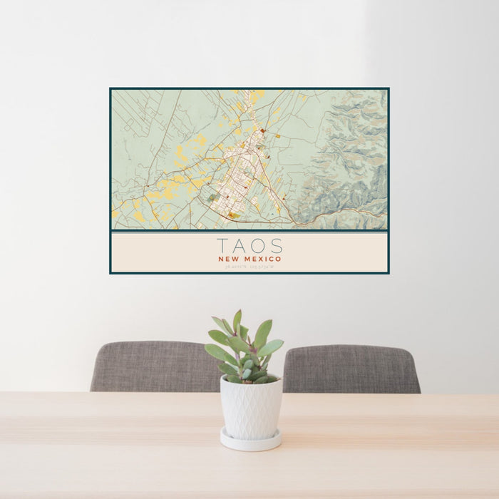 24x36 Taos New Mexico Map Print Lanscape Orientation in Woodblock Style Behind 2 Chairs Table and Potted Plant