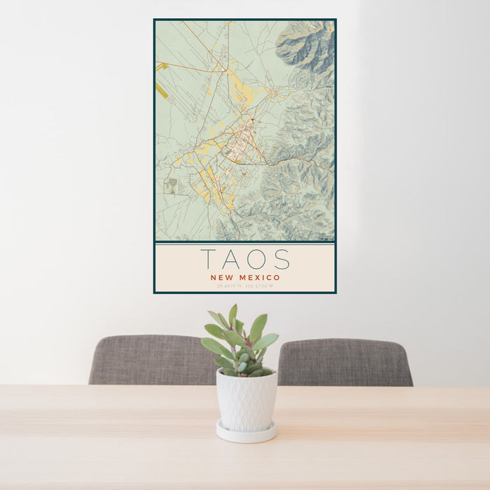 24x36 Taos New Mexico Map Print Portrait Orientation in Woodblock Style Behind 2 Chairs Table and Potted Plant